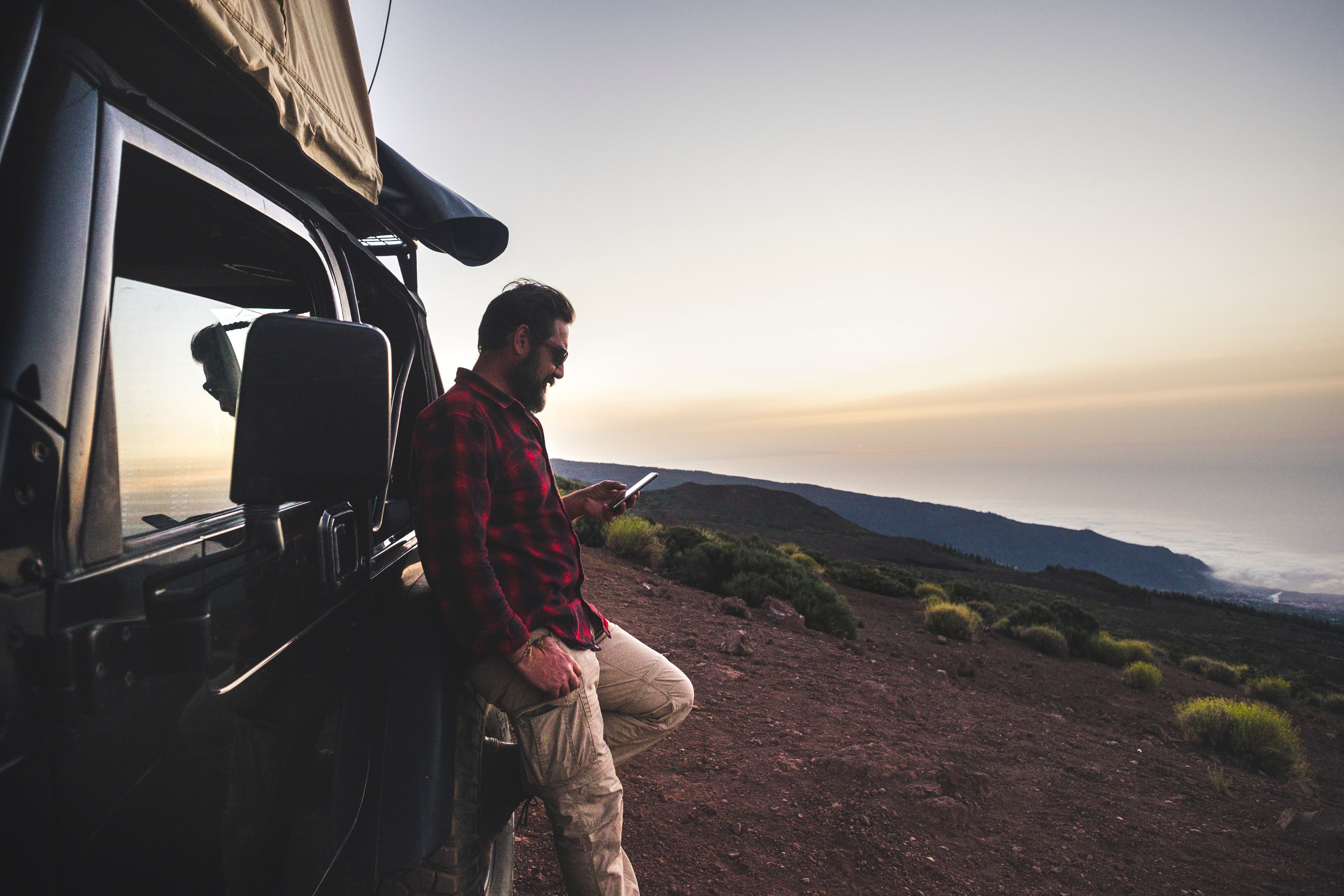 Man sitting outdoors using his phone with a coverage icon above him