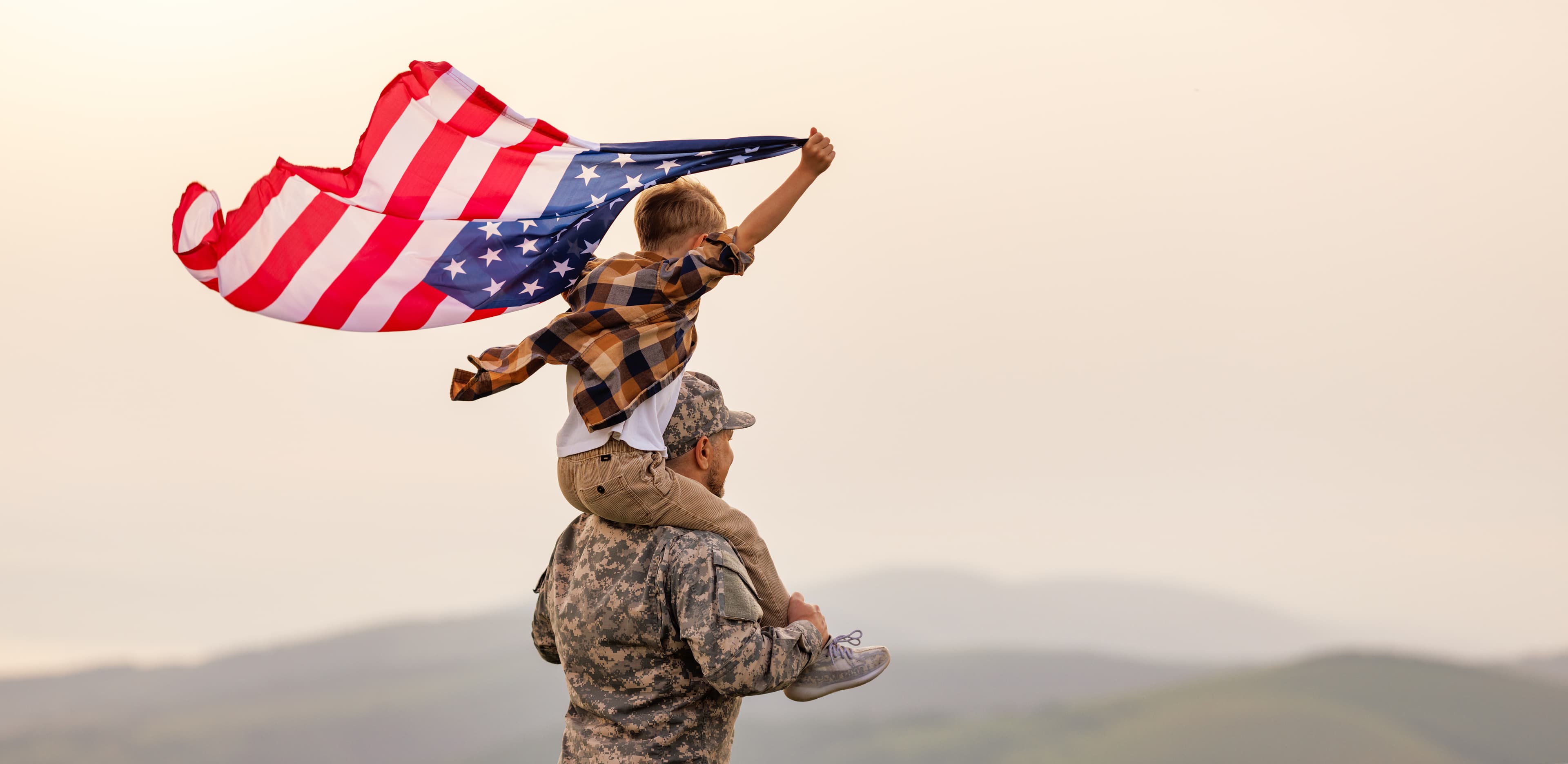 Child holding an American flag on a soldier’s shoulders