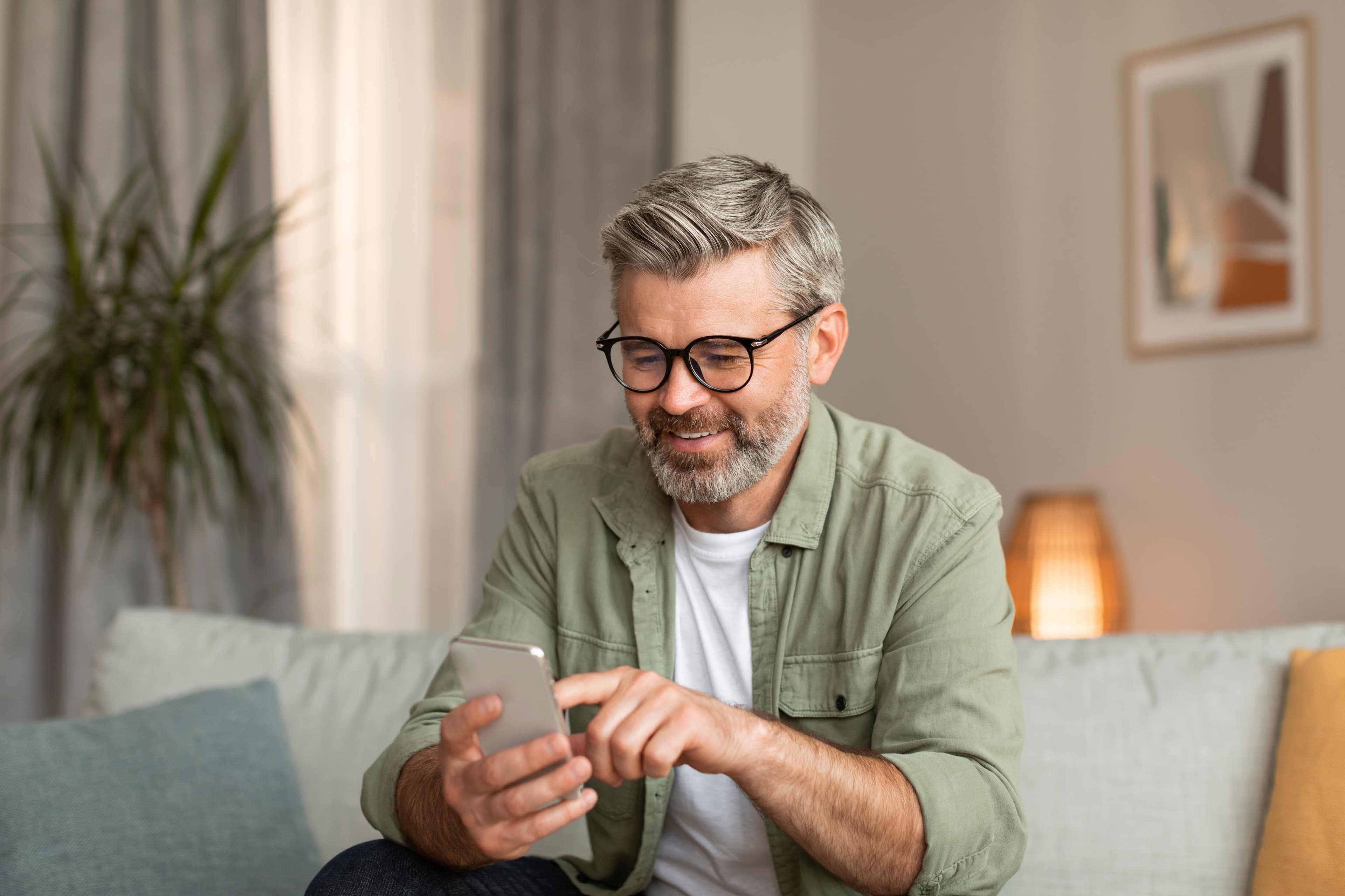 Man smiling while using a phone on a couch
